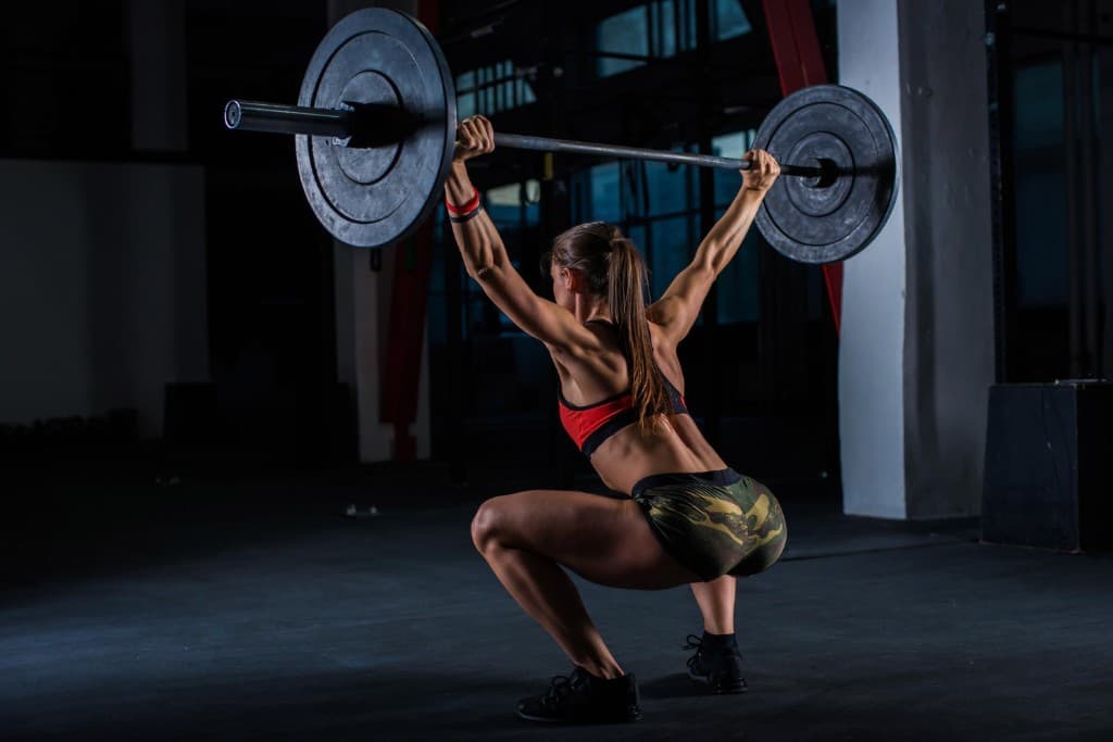 Athlète à la box en squat overhead, barre chargée au-dessus de la tête — entraînement CrossFit