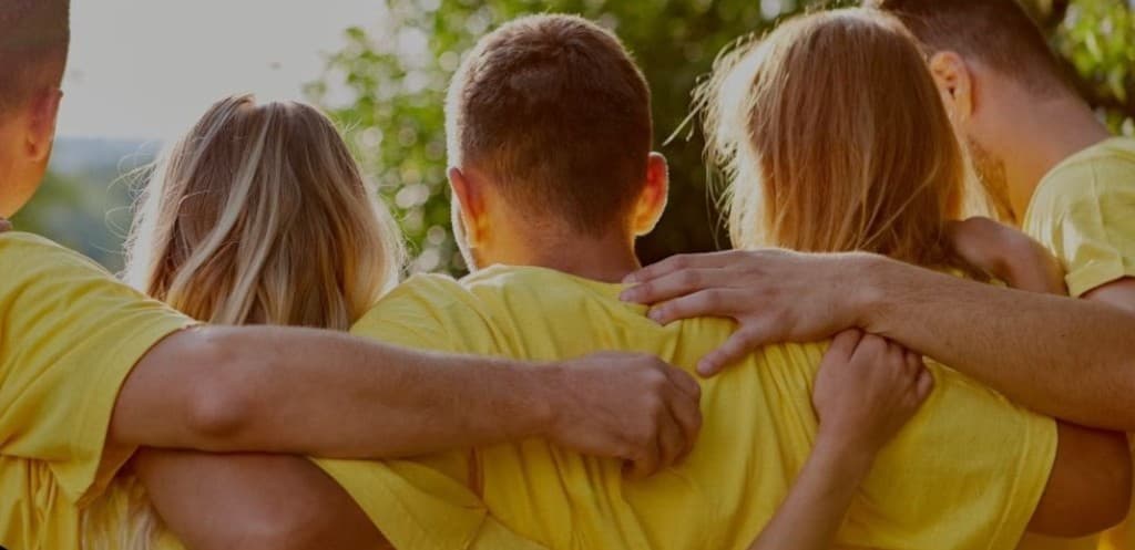 Équipe en t-shirts jaunes, bras sur les épaules — team building et cohésion de groupe